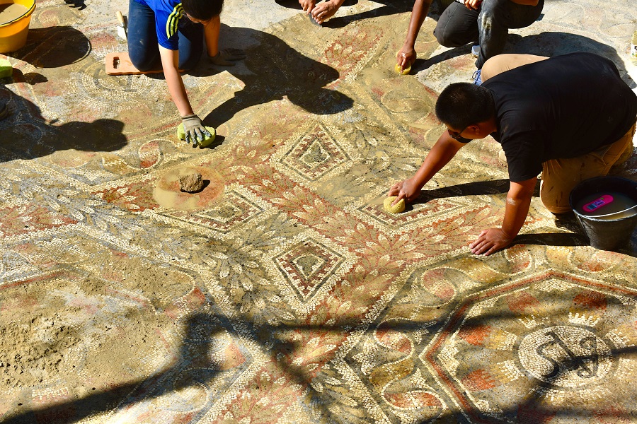 Students cleaning a mosaic